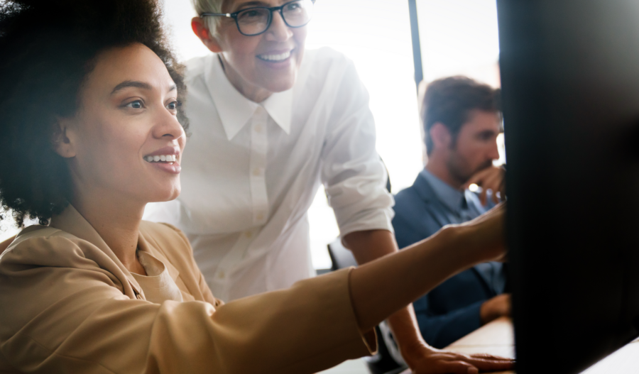 Een vrouw lacht en wijst naar een scherm.