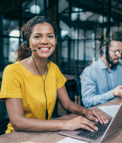 Een vrouw lacht en wijst naar een scherm.
