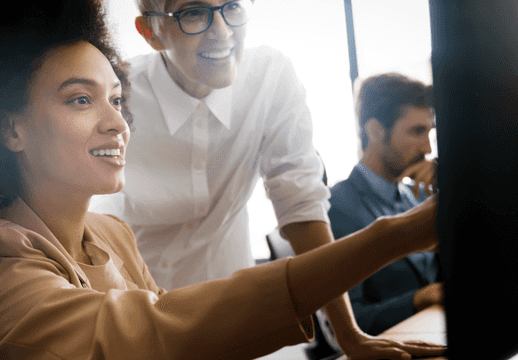 Une femme souriante pointant vers un écran.