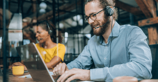 Guy smiling when working as support via a computer.