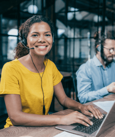 Une femme souriante pointant vers un écran.