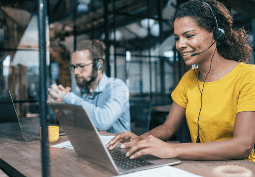 Une femme souriante travaillant en tant que support à l'aide d'un ordinateur portable.